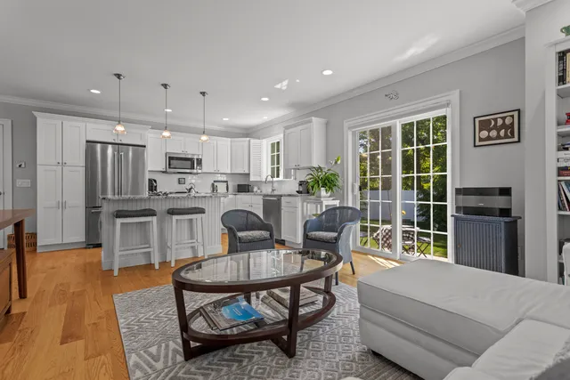 a living room with stainless steel appliances furniture a rug and a kitchen view