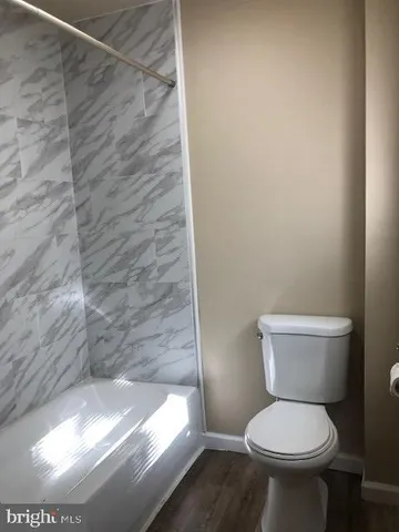 a white toilet sitting in a bathroom next to a wooden wall