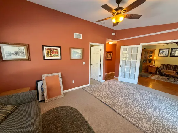 an empty room with a chandelier fan and windows