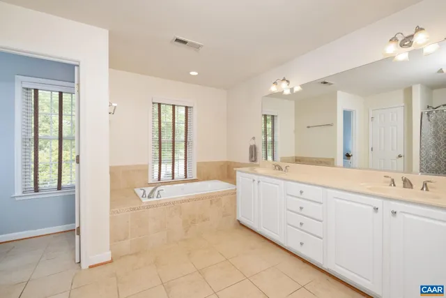 a spacious bathroom with a double vanity sink large mirror and a bathtub