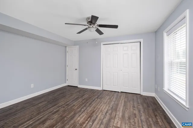 a view of empty room with wooden floor and fan