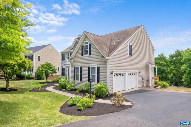 a view of a white house next to a yard with potted plants