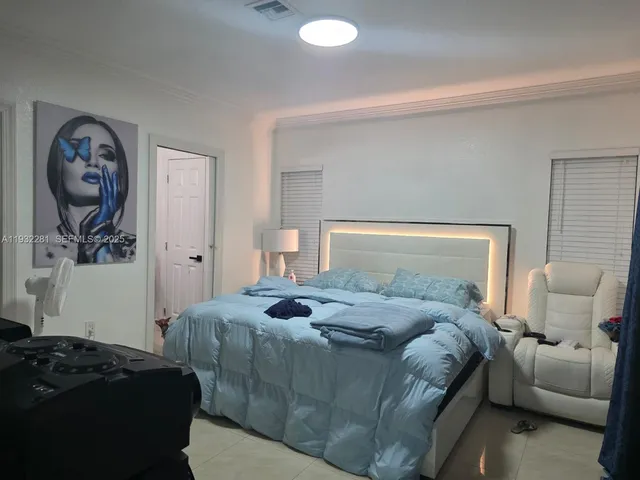 a bedroom with a bed and a lamp on dresser