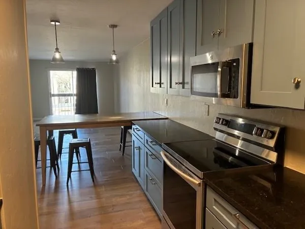 a kitchen with stainless steel appliances granite countertop a sink wooden cabinets and a stove