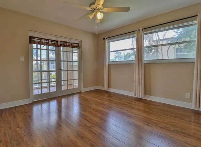 a view of an empty room with wooden floor and a window