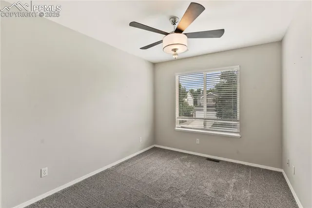 an empty room with a ceiling fan and window