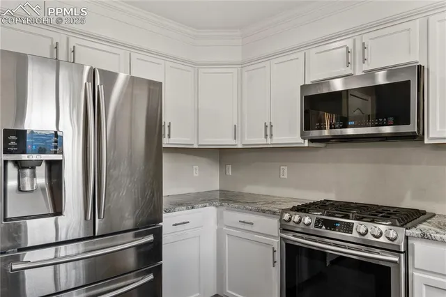 a kitchen with stainless steel appliances white cabinets white stove a microwave and a refrigerator