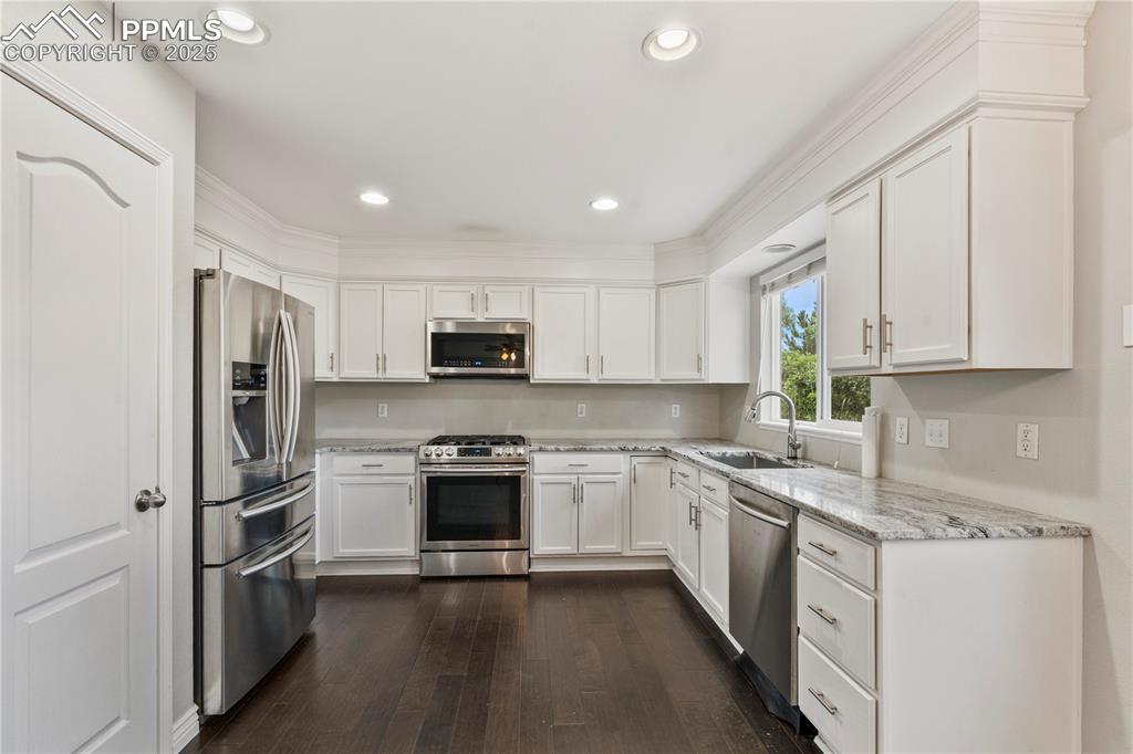 3320 Tail Spin Drive Colorado Springs, CO 80916 - Photo 8 of 28 a kitchen with stainless steel appliances granite countertop a refrigerator a stove top oven a sink and cabinets