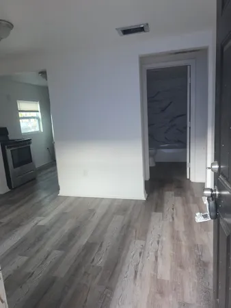 a view of an empty room with wooden floor and a window