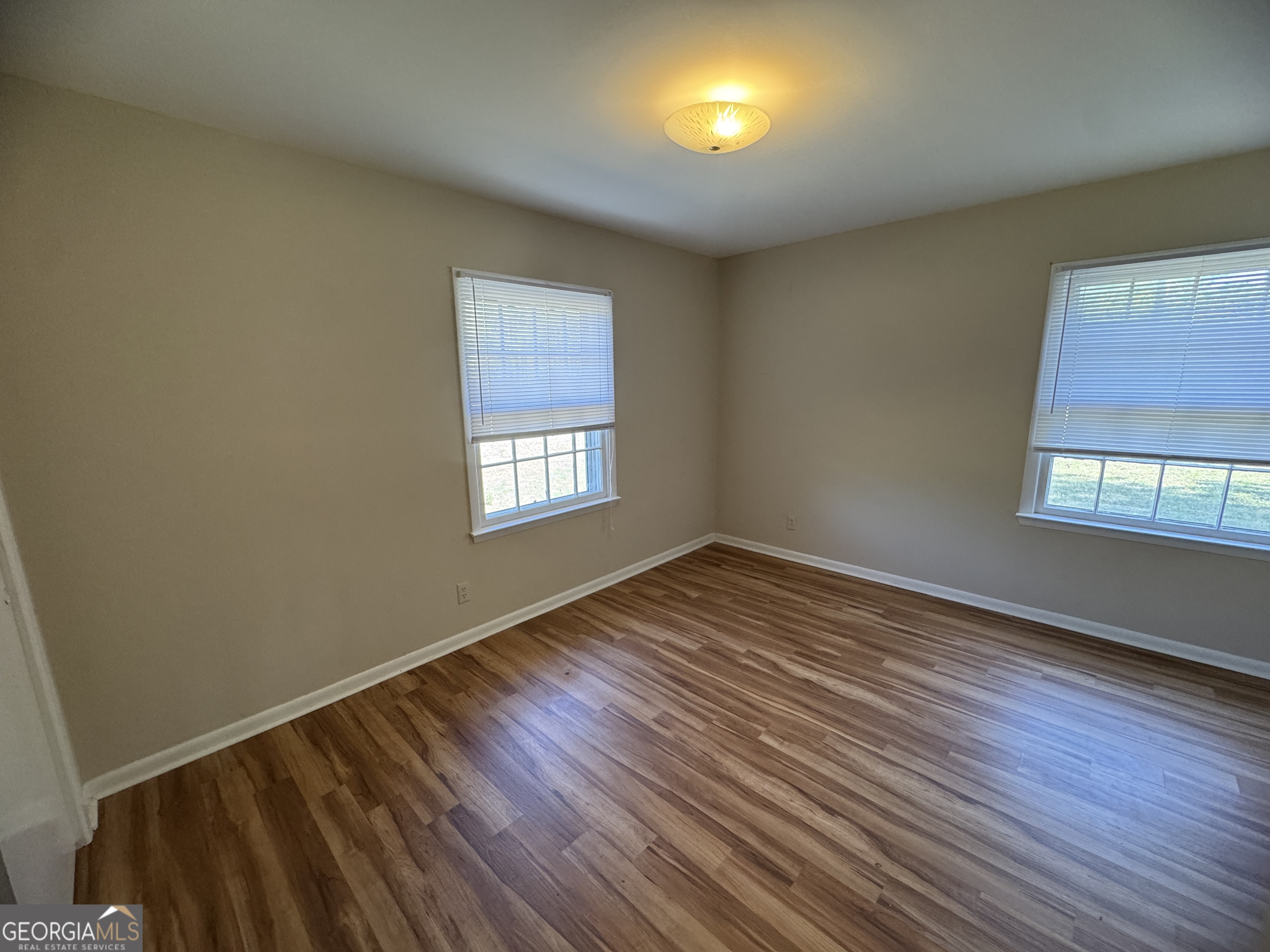 7290 Nevils Groveland Road Pembroke, GA 31321 - Photo 40 of 45 an empty room with wooden floor and windows