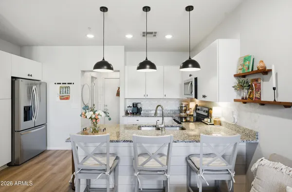 a kitchen with stainless steel appliances kitchen island granite countertop a table chairs and a refrigerator