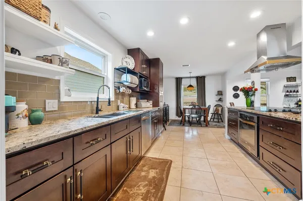 a kitchen with stainless steel appliances granite countertop a sink and a refrigerator