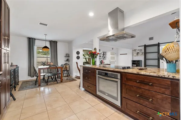 a kitchen with kitchen island granite countertop a sink and cabinets
