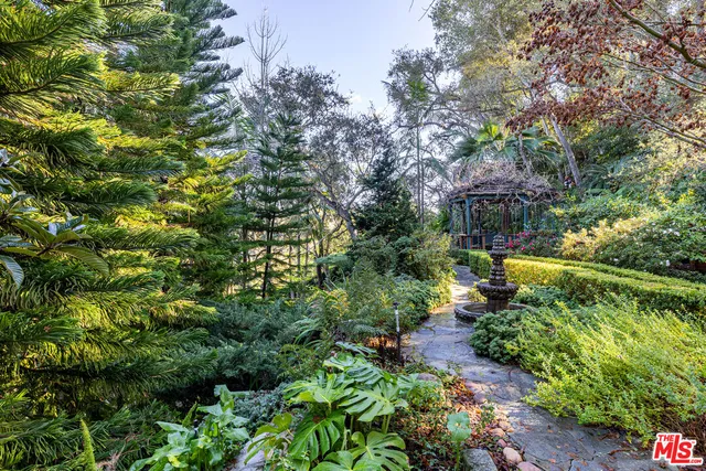 a front view of a house with a yard and fountain in middle