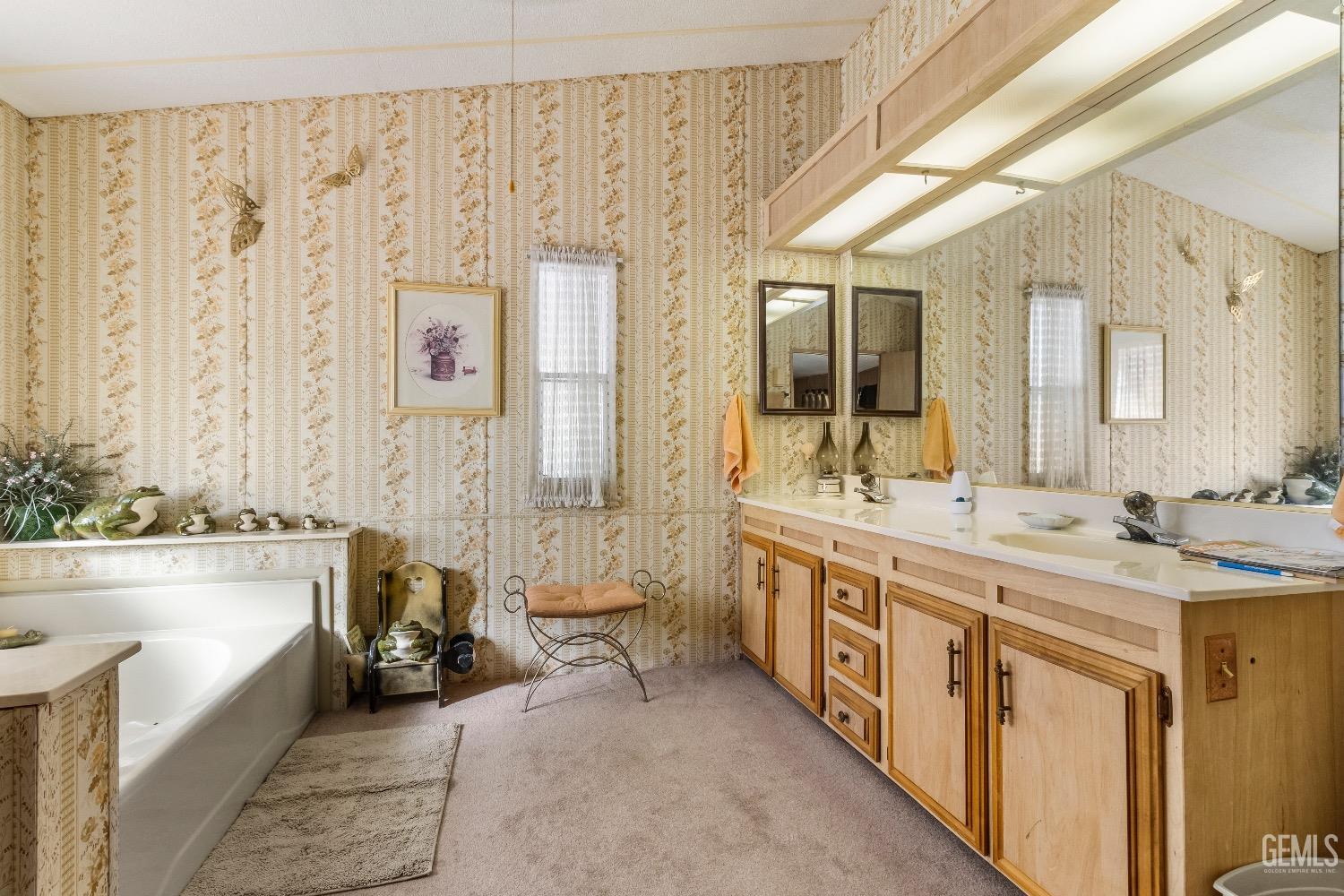 a spacious bathroom with a double vanity sink a mirror a bathtub and next to a window