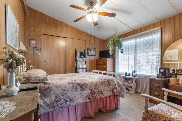a bedroom with a bed a couch and large windows