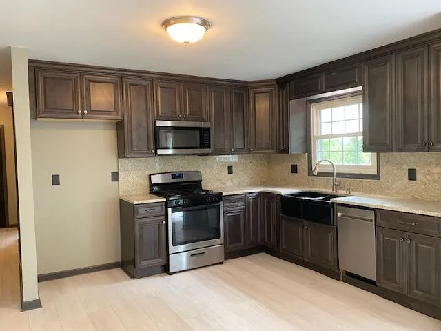 a kitchen with stainless steel appliances granite countertop a stove a sink dishwasher a refrigerator and a microwave oven