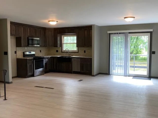 a large kitchen with kitchen island granite countertop a stove top oven a sink and dishwasher a refrigerator with wooden floor