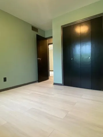a view of an empty room with closet and a bathroom