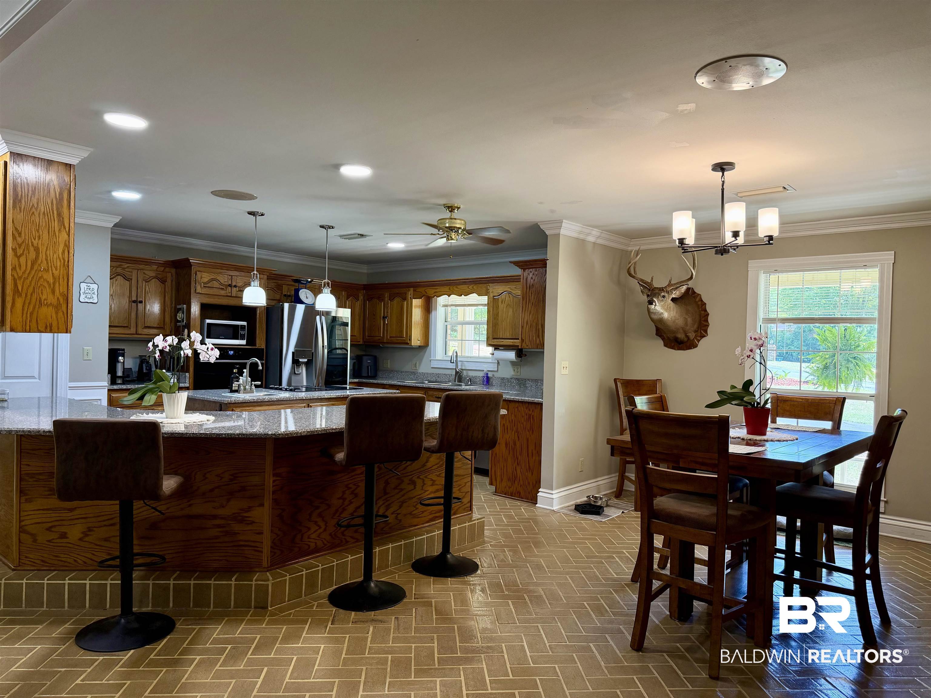2944 Appleton Road Brewton, AL 36426 - Photo 6 of 65 Kitchen featuring wood finish cabinetry, light stone counters, stainless steel appliances, a kitchen breakfast bar, and ornamental molding