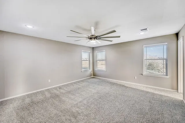 an empty room with windows and fan