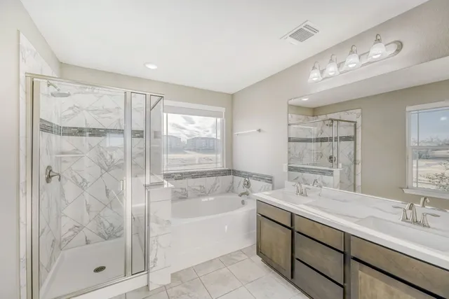 a bath room with a sink vanity tub shower and a mirror