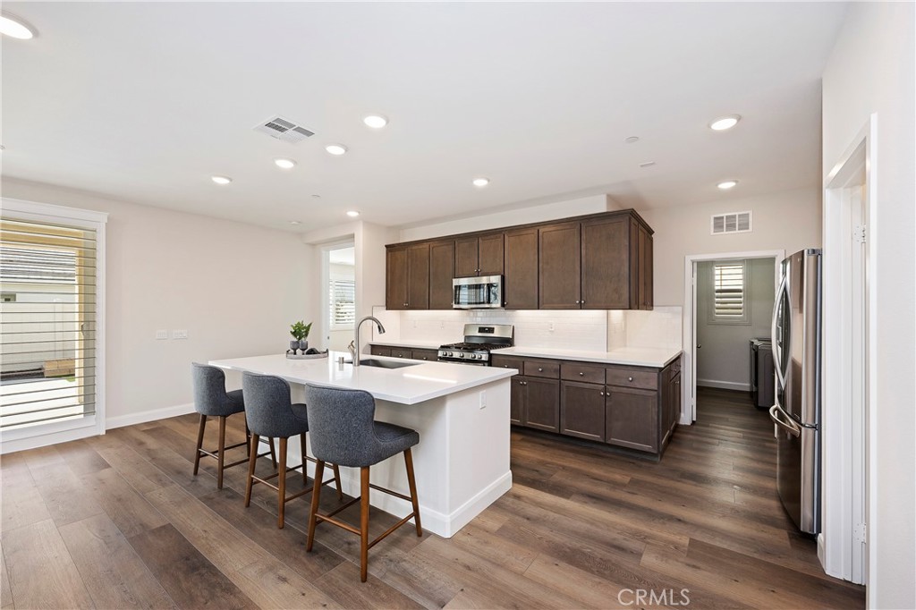 34709 Candlestick Circle Murrieta, CA 92563 - Photo 8 of 40 a kitchen with stainless steel appliances a kitchen island hardwood floor sink stove dining table and chairs