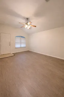 an empty room with chandelier fan and fireplace