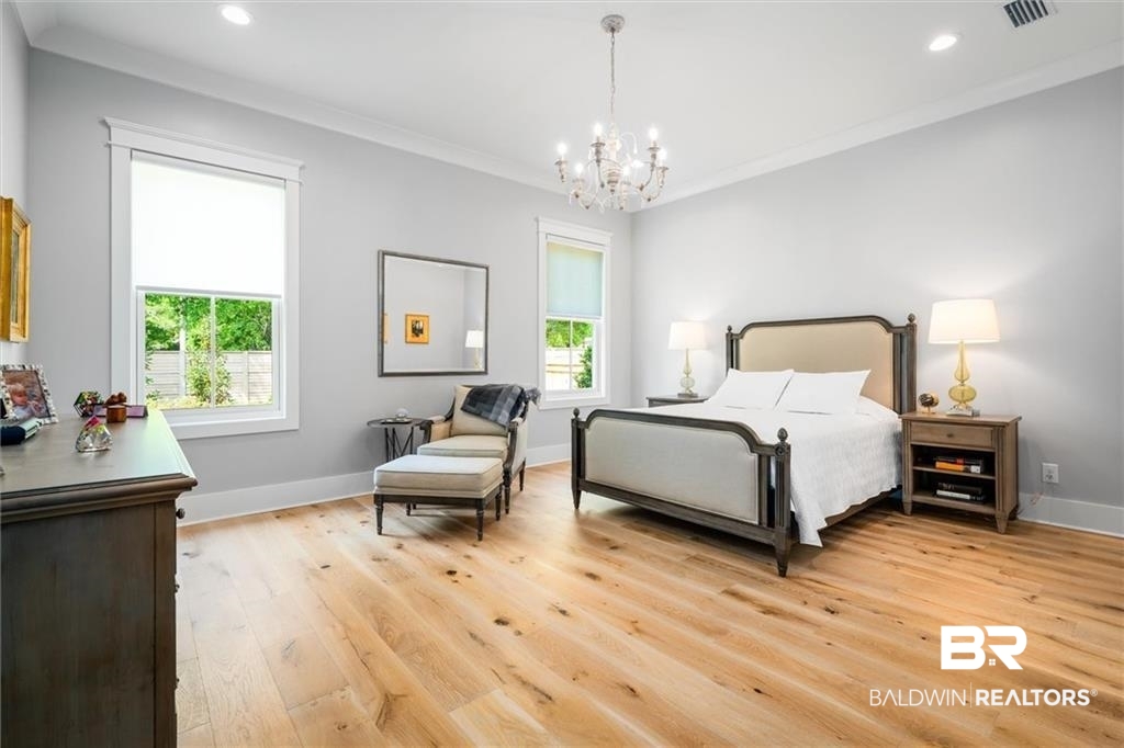 707 Cardamel Court Fairhope, AL 36532 - Photo 17 of 40 Bedroom with crown molding, a chandelier, and light hardwood / wood-style flooring