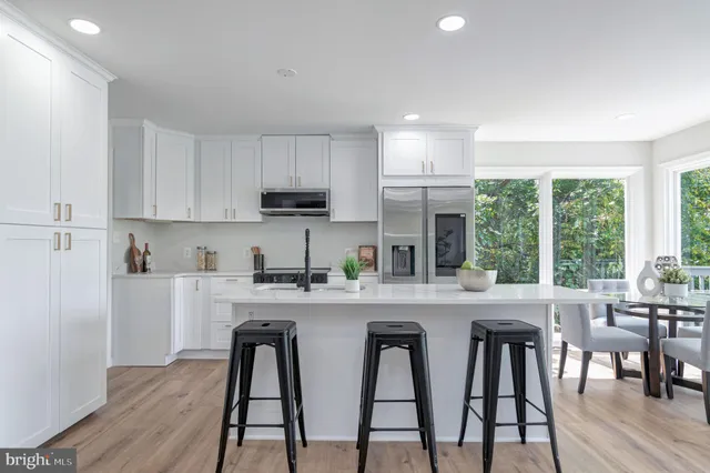 a kitchen with stainless steel appliances granite countertop a table chairs refrigerator and wooden cabinets
