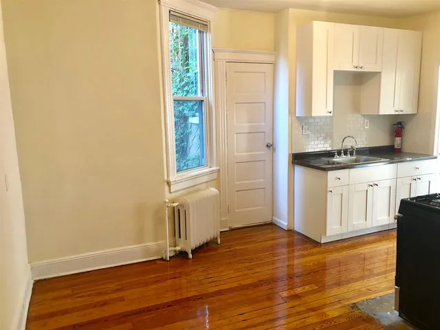 a view of a kitchen with wooden floor and a window