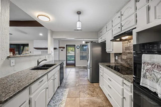 a kitchen with granite countertop kitchen island stainless steel appliances a sink stove top oven and cabinets