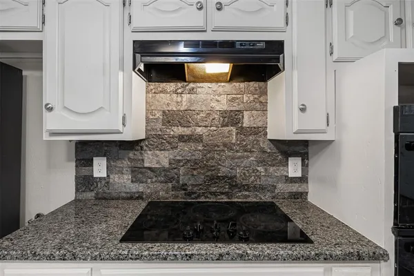 a kitchen with white cabinets and a stove