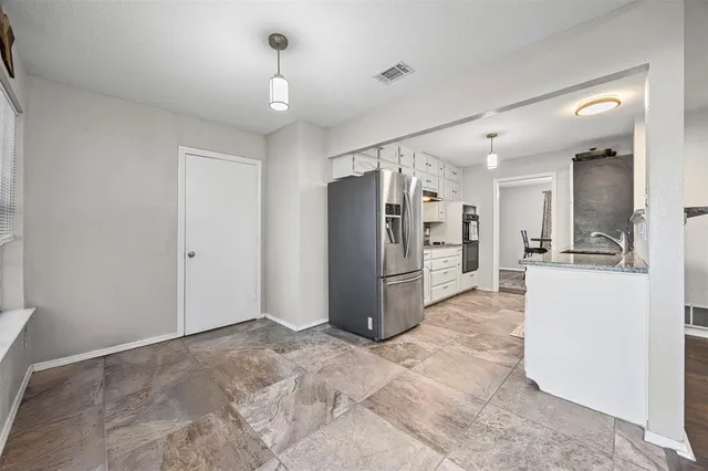 a view of a kitchen with refrigerator and white cabinets