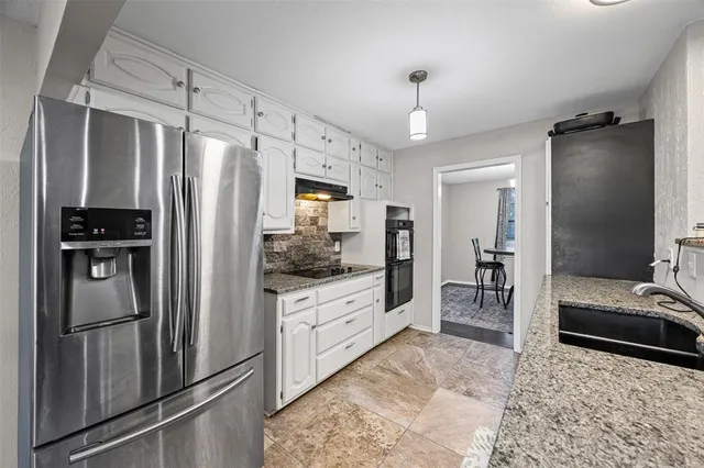 a kitchen with granite countertop a refrigerator and a sink
