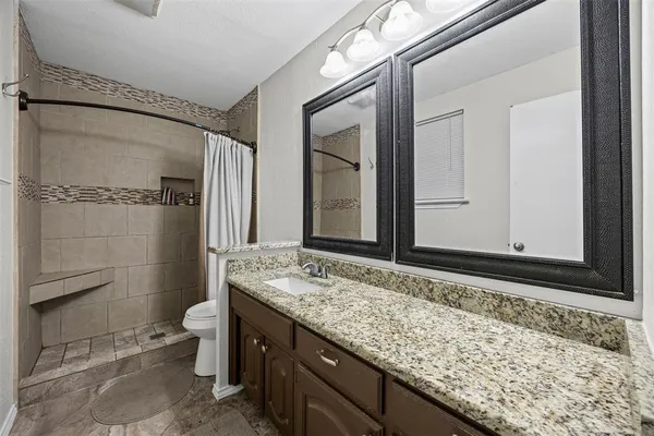 a bathroom with a granite countertop sink toilet and shower