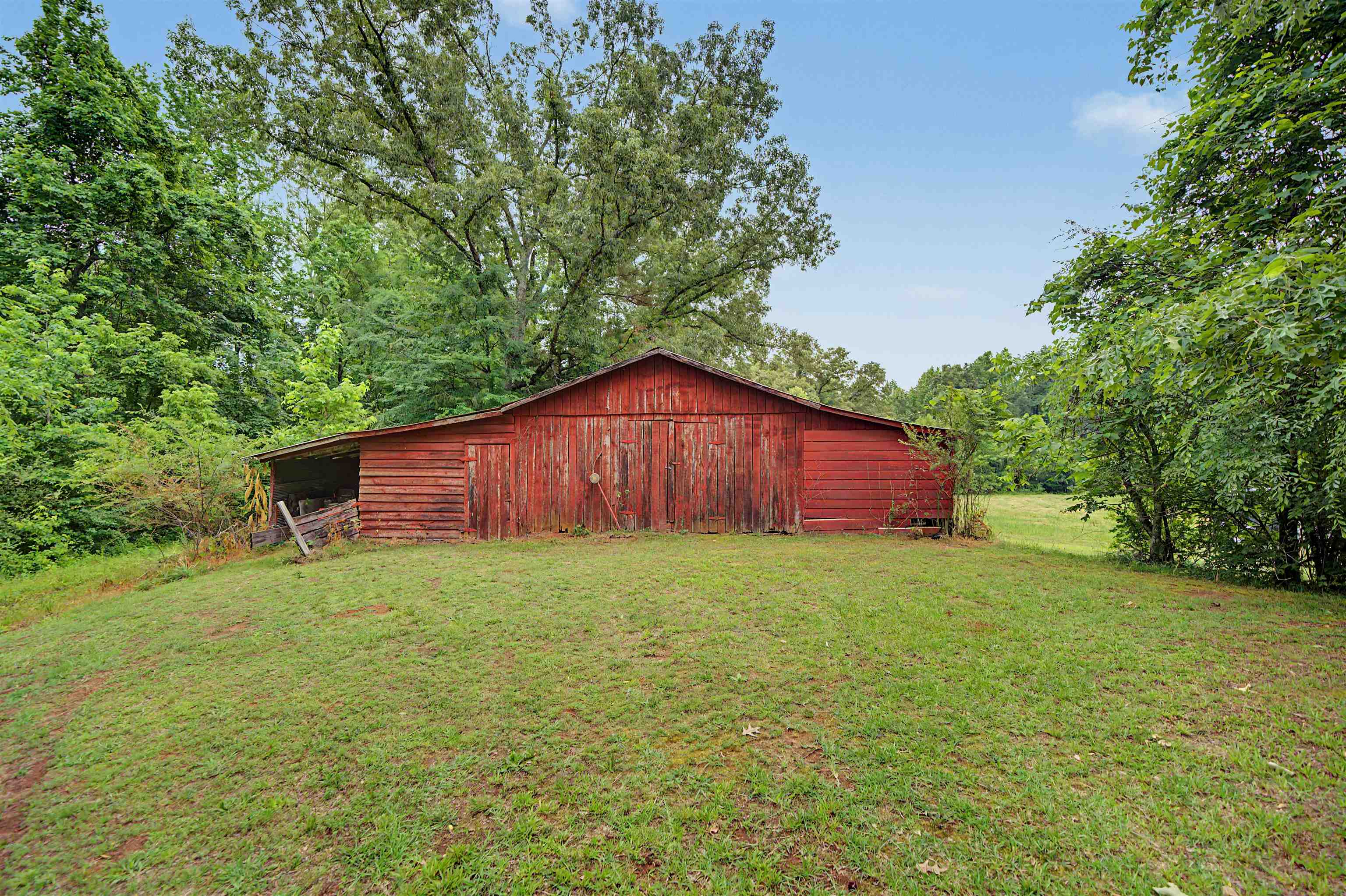 336 57th Highway West Ramer, TN 38367 - Photo 39 of 39 Red barn structure featuring horizontal siding, a gabled roof, and attached open-sided storage