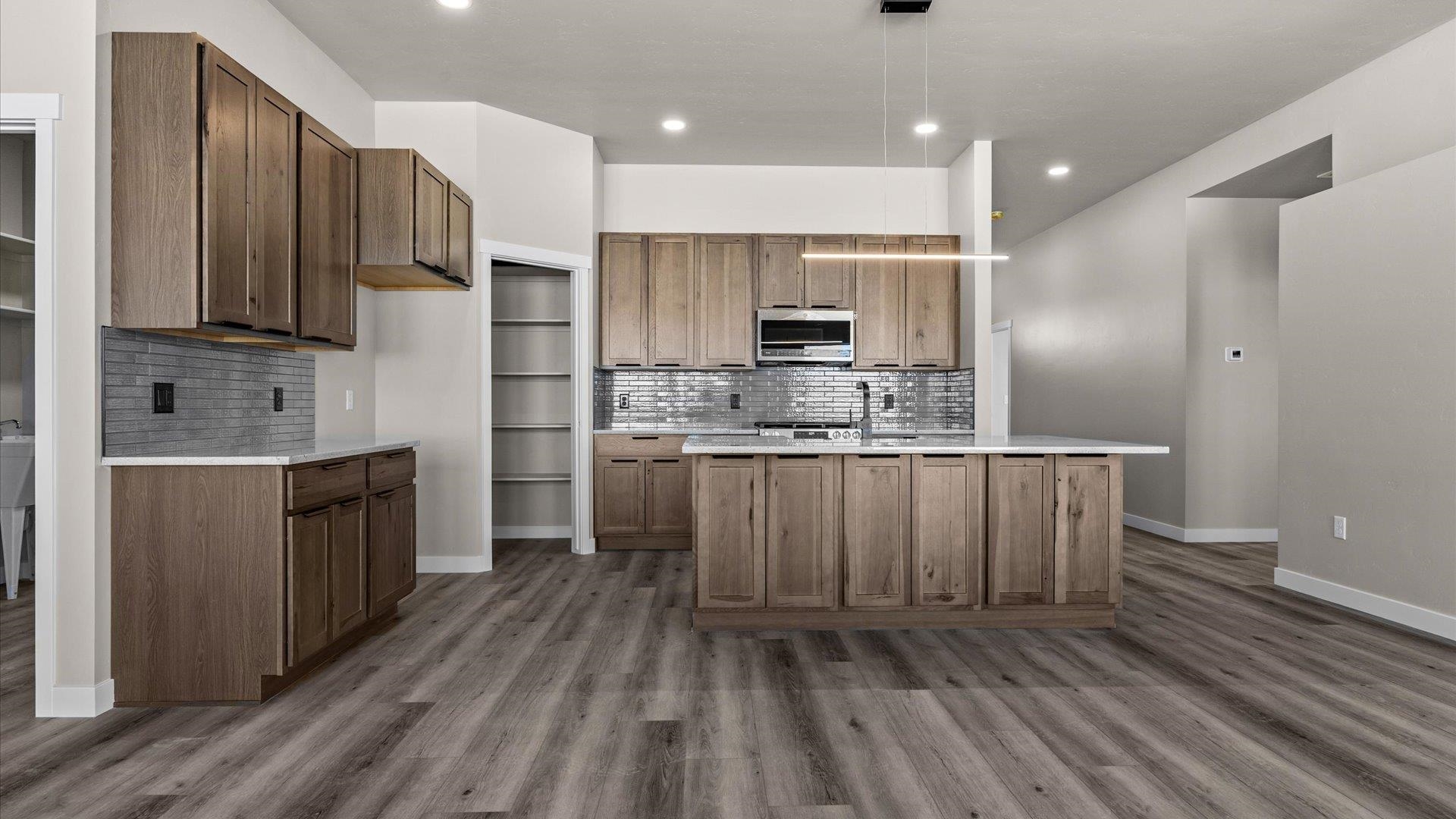 3066 Thunderhead Way Grand Junction, CO 81504 - Photo 16 of 30 a kitchen with kitchen island granite countertop wooden floors stainless steel appliances a sink and a refrigerator