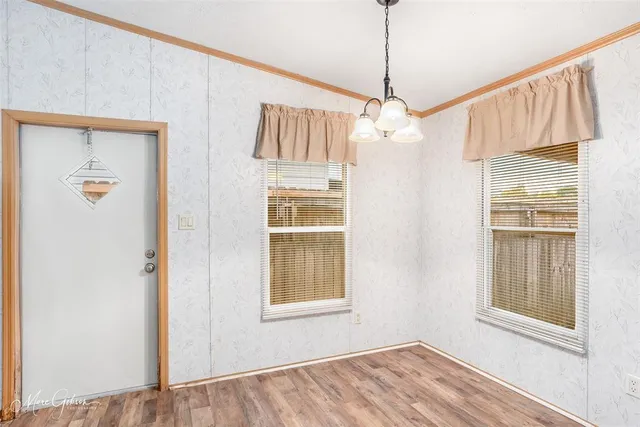 a view of an empty room with wooden floor and windows