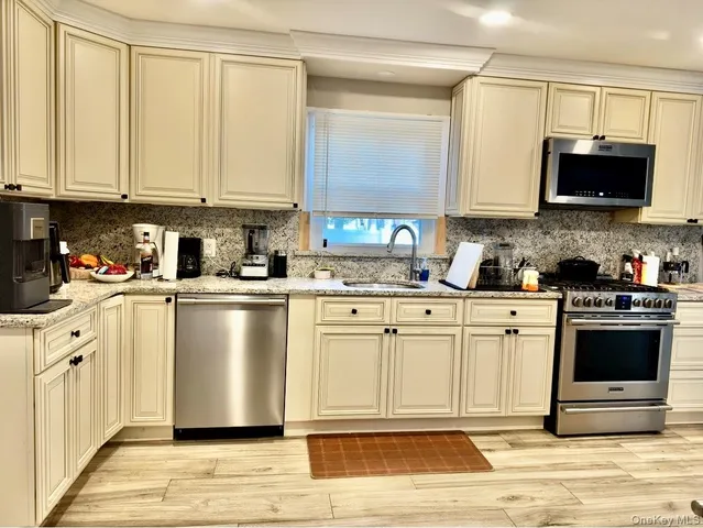 a kitchen with stainless steel appliances granite countertop a stove a sink and a microwave