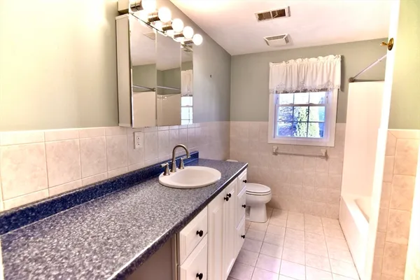 a bathroom with a granite countertop sink a toilet a mirror and window