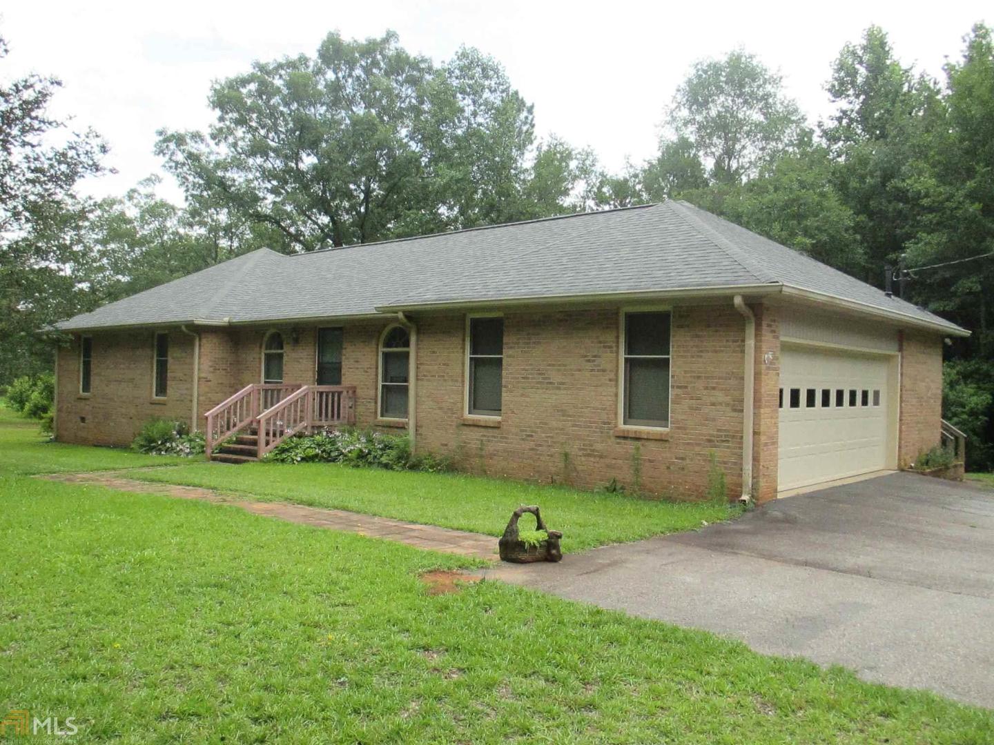 a view of a house with a yard plants and large tree