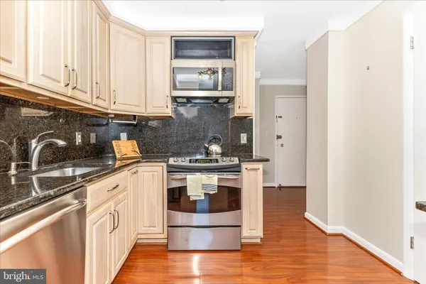 a kitchen with stainless steel appliances granite countertop a stove and white cabinets