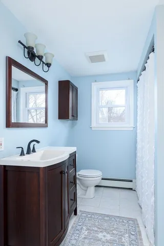 a bathroom with a toilet a sink a mirror and a window