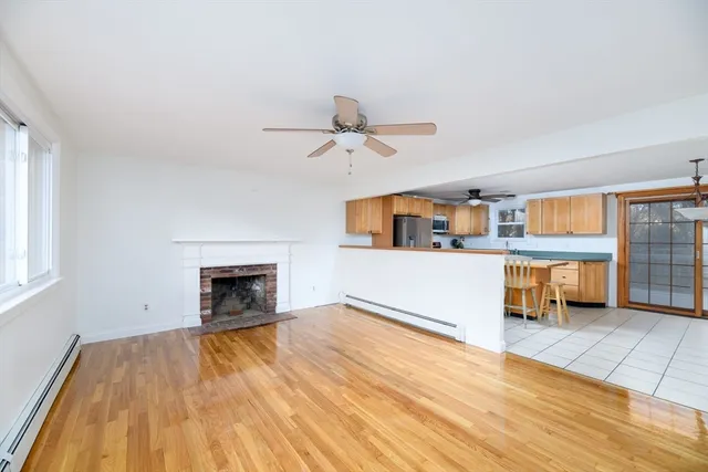wooden floor in an empty room with a fireplace and a window