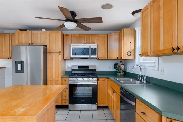 a kitchen with stainless steel appliances granite countertop a sink a stove a refrigerator cabinets and a window