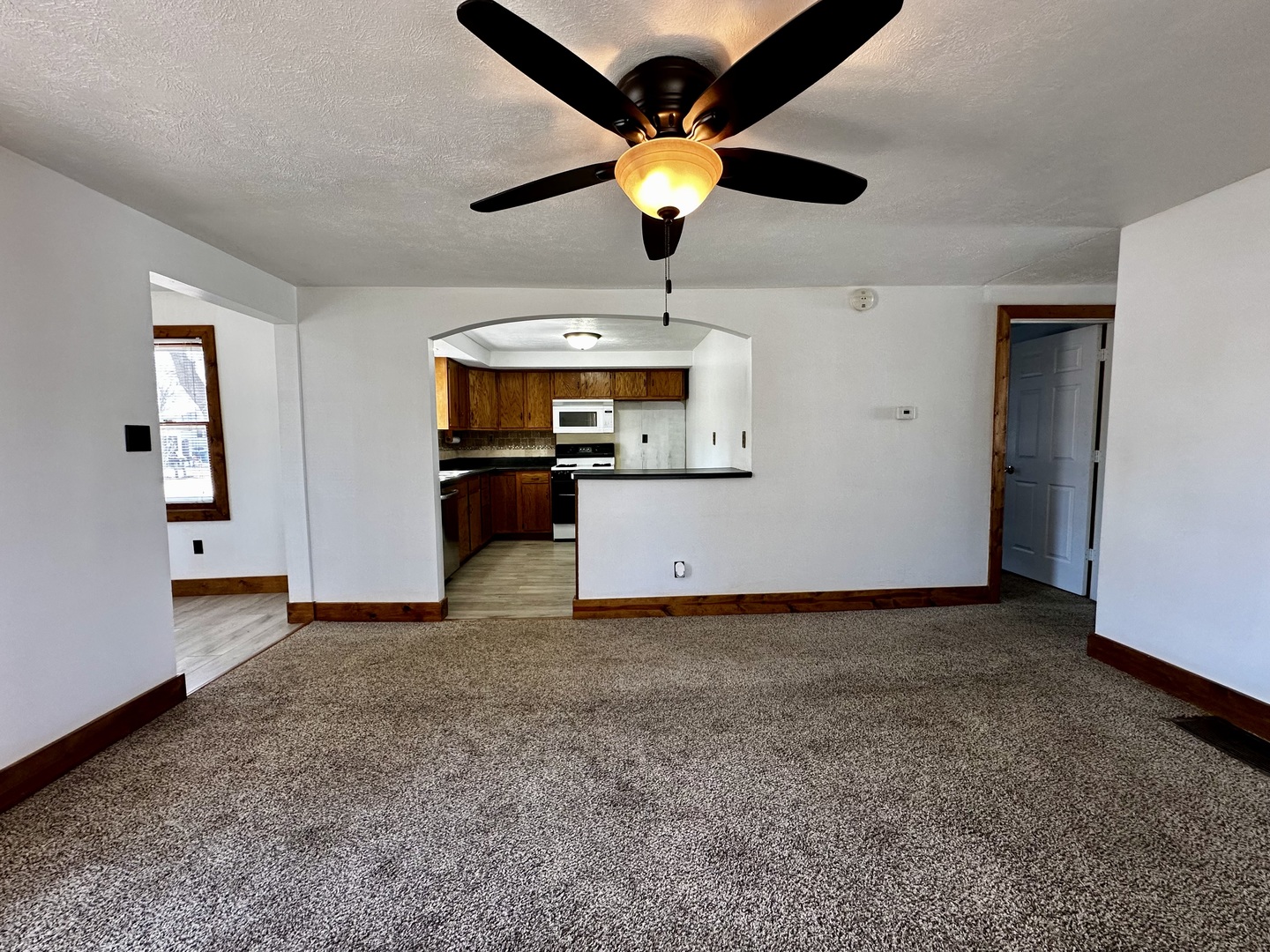 1619 East Washington Street Clinton, IL 61727 - Photo 8 of 32 a view of a kitchen with a stove cabinets a ceiling fan and wooden floor