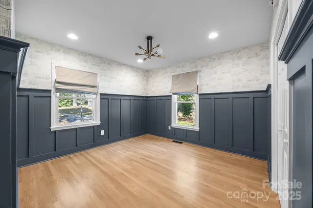 a view of an empty room with a window and a kitchen