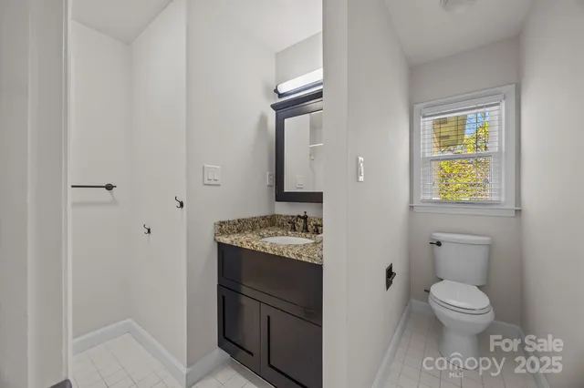 a bathroom with a granite countertop toilet and a sink