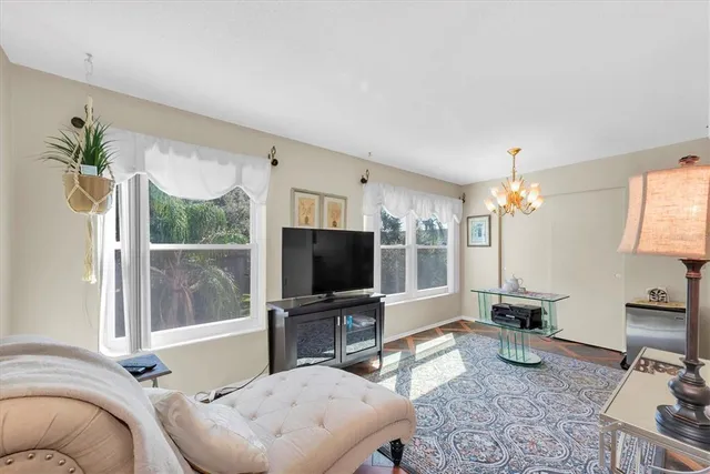 a living room with furniture a chandelier and a flat screen tv
